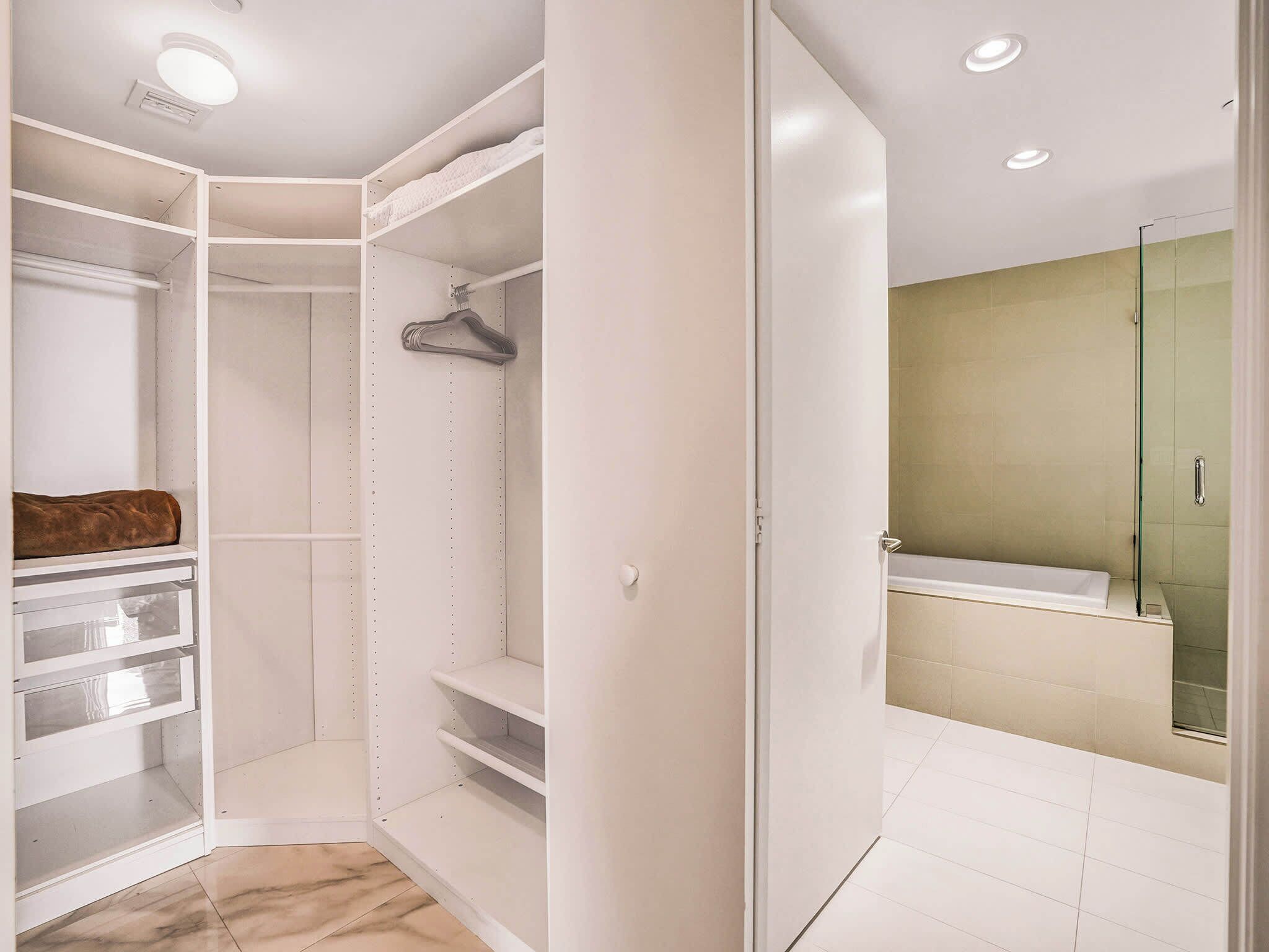 A walk-in closet with open shelves, a hanging rod, and a brown item on the left.