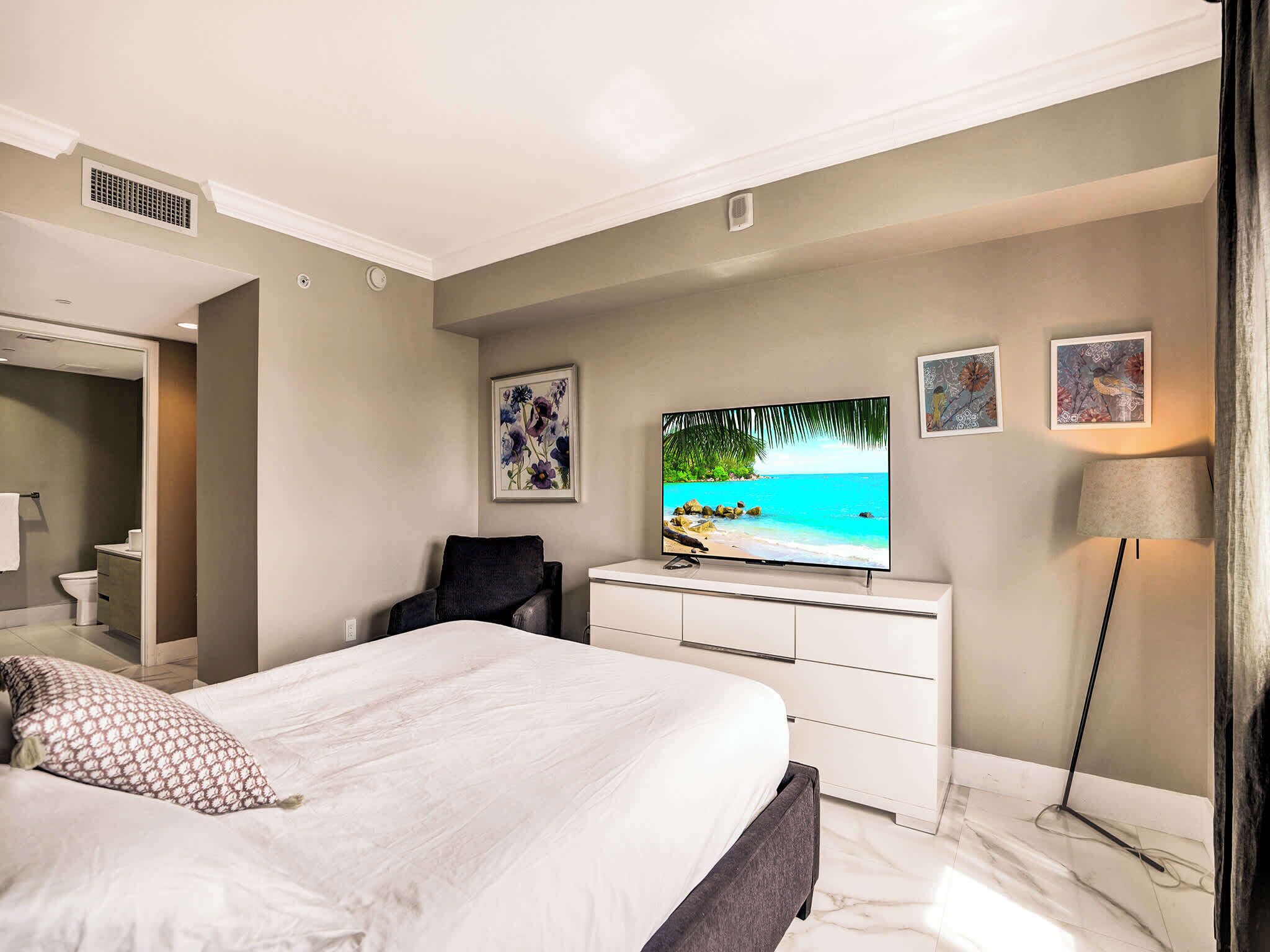 Hotellihuone, jossa on sänky, televisio, työpöytä ja tuoli.
