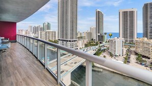 A balcony with a view of a cityscape, including high-rise buildings and a body of water.