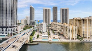 A high-rise urban area with multiple tall buildings, a bridge, and a body of water.