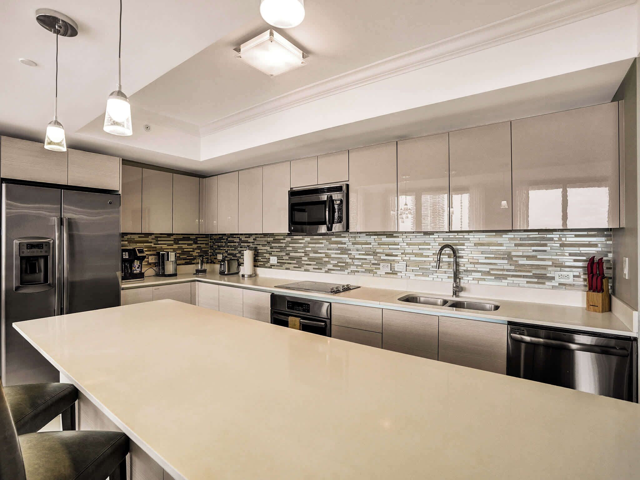 A modern kitchen with stainless steel appliances, a large island, and a tiled backsplash.
