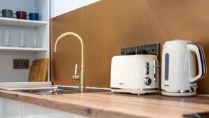 Eine Küche mit Holzarbeitsplatte, Spüle aus Edelstahl, einem weißen Toaster und einer weißen Kaffeemaschine.