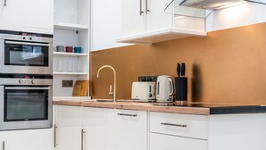 Eine moderne Küche mit eingebauten Backöfen, einer Kaffeemaschine und einem Messerblock.