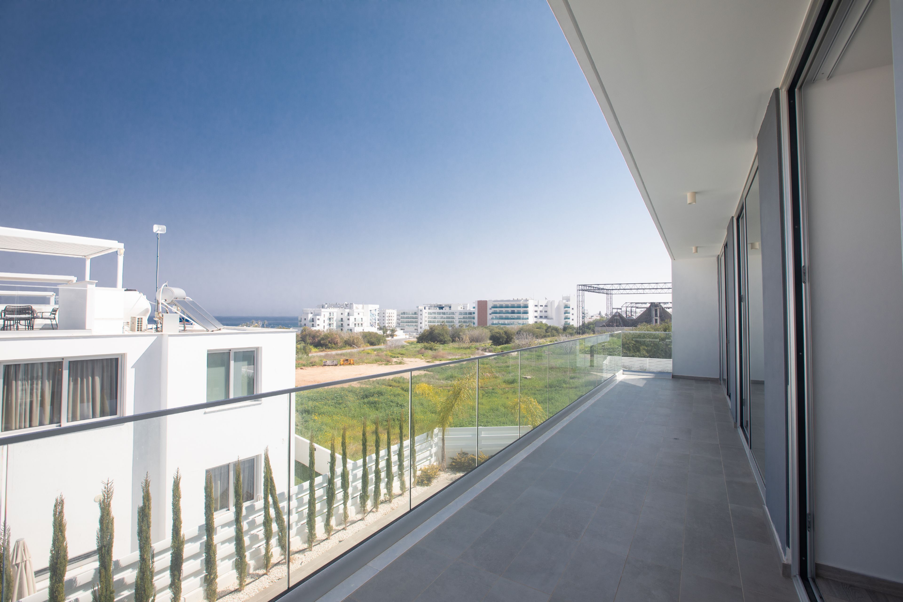 A modern balcony with a clear view of the cityscape and greenery below.