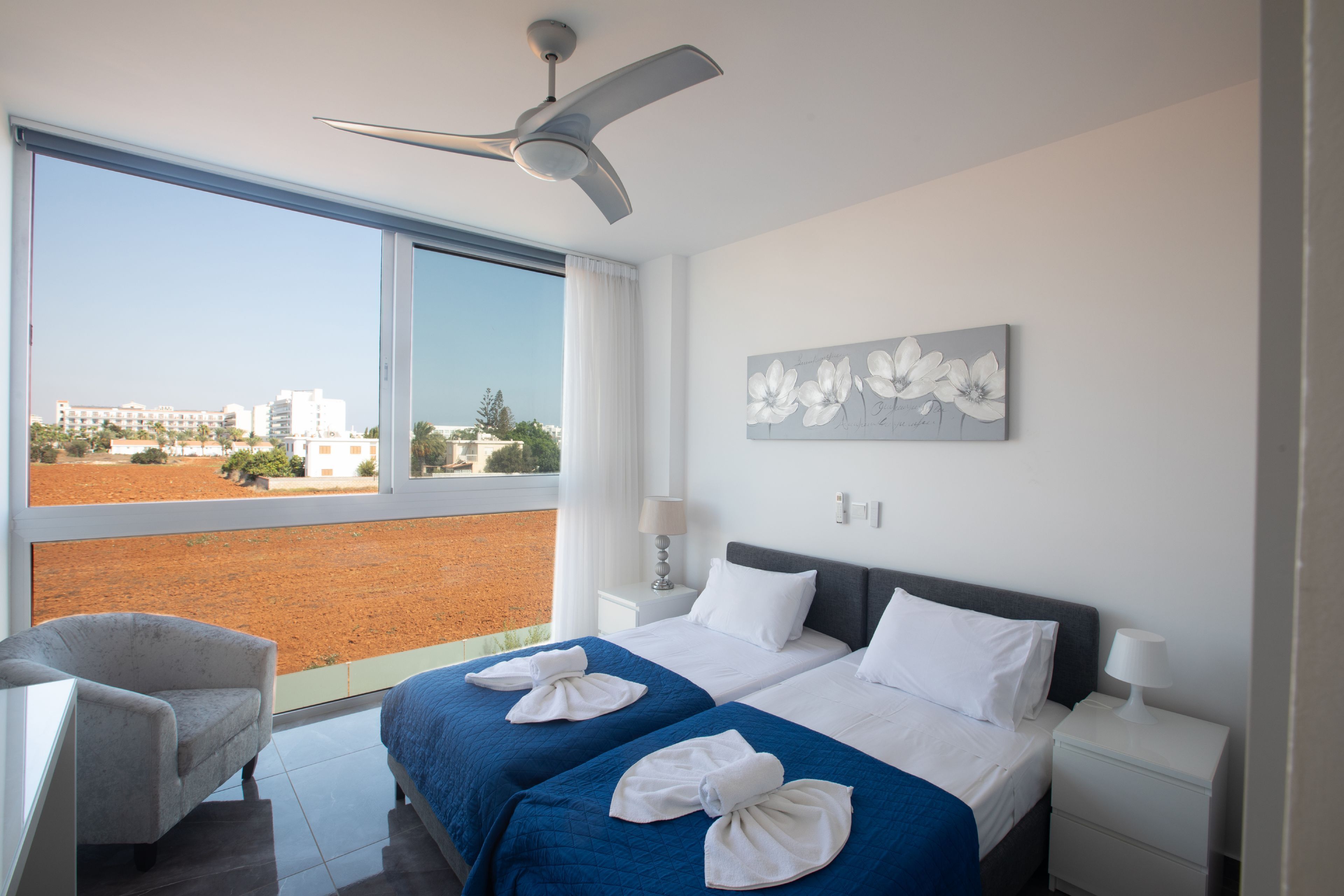 A hotel room with two beds, a view of the city, and a ceiling fan.