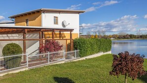 Una casa moderna con fachada blanca y amarilla, una antena parabólica y vistas a un lago.