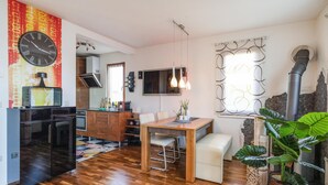 Una cocina moderna con un refrigerador negro, armarios de madera y un comedor con una mesa y sillas de madera.