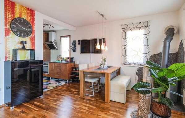 Une cuisine moderne avec un réfrigérateur noir, des meubles de rangement en bois et un coin repas comprenant une table et des chaises en bois.