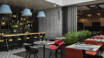 A modern restaurant with a bar area, multiple seating arrangements, and decorative plants.