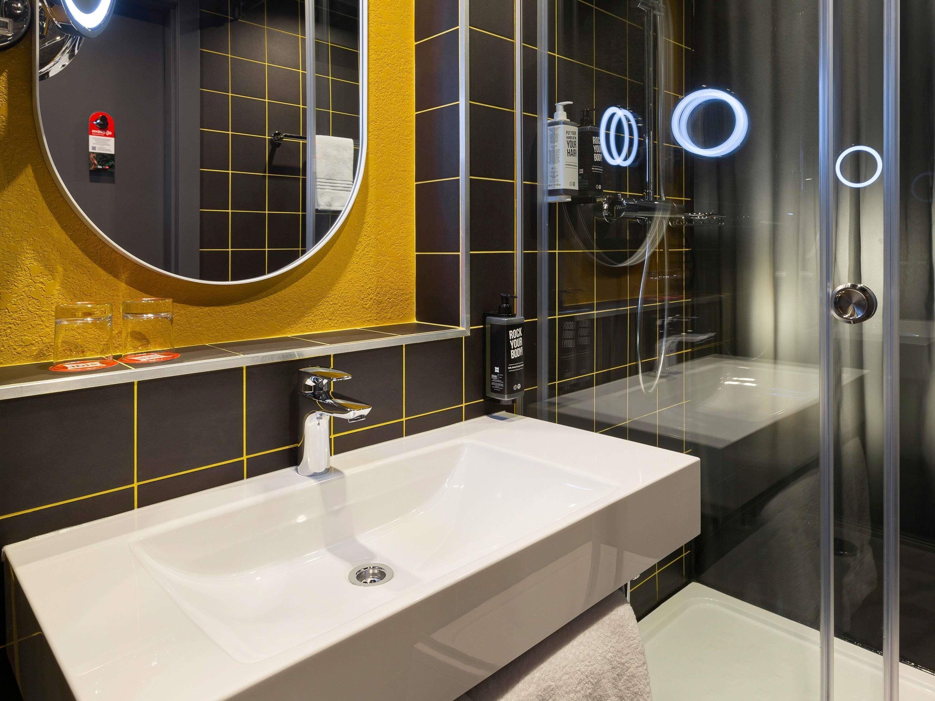 Ein modernes Badezimmer mit einem weißen Waschbecken, einem großen Spiegel und einer Duschkabine.