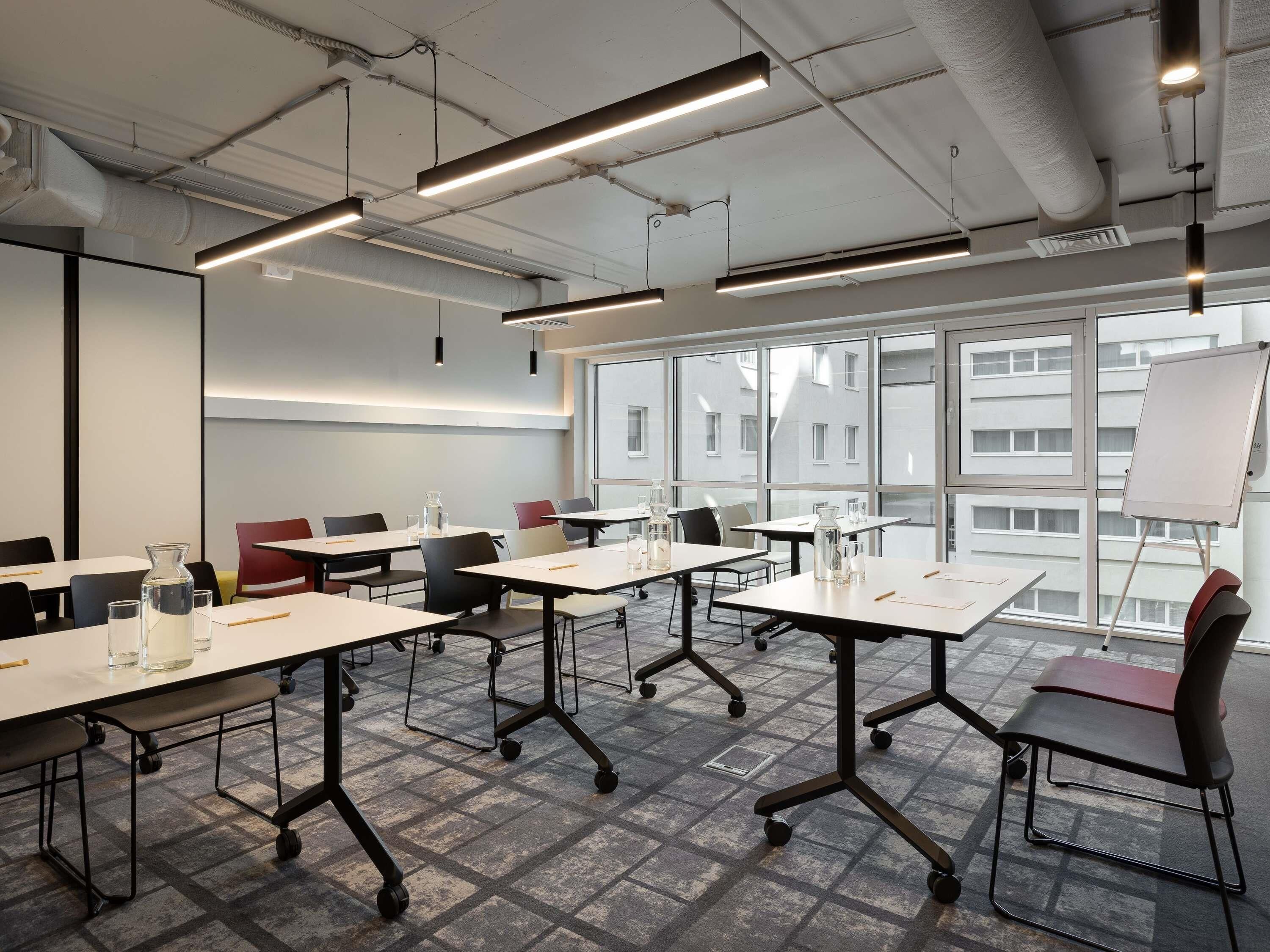 A modern conference room with tables, chairs, and a whiteboard.