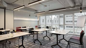 A modern conference room with tables, chairs, and a whiteboard.