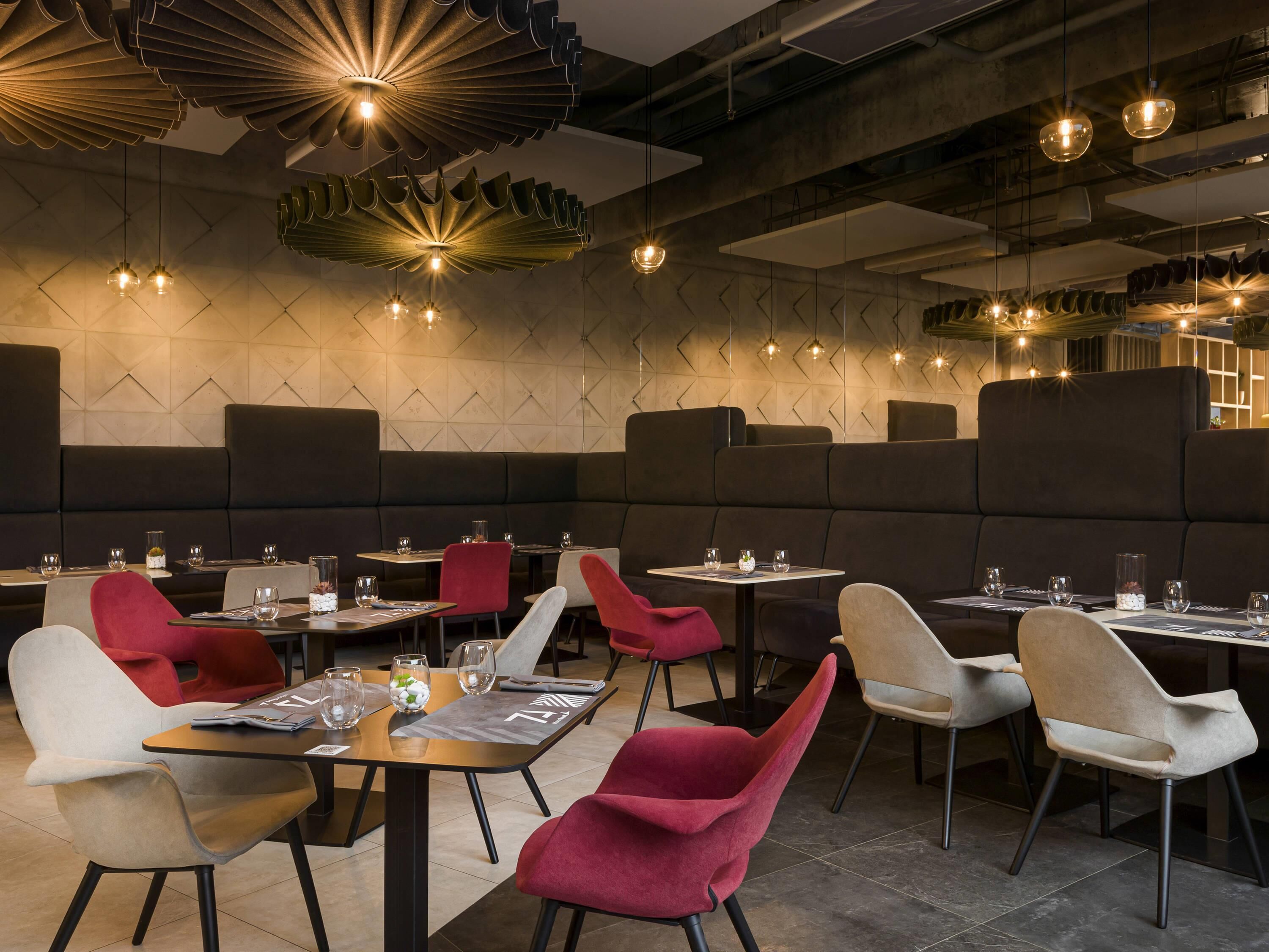 Un interior de restaurante moderno con mesas altas, sillas acolchadas e iluminación contemporánea.