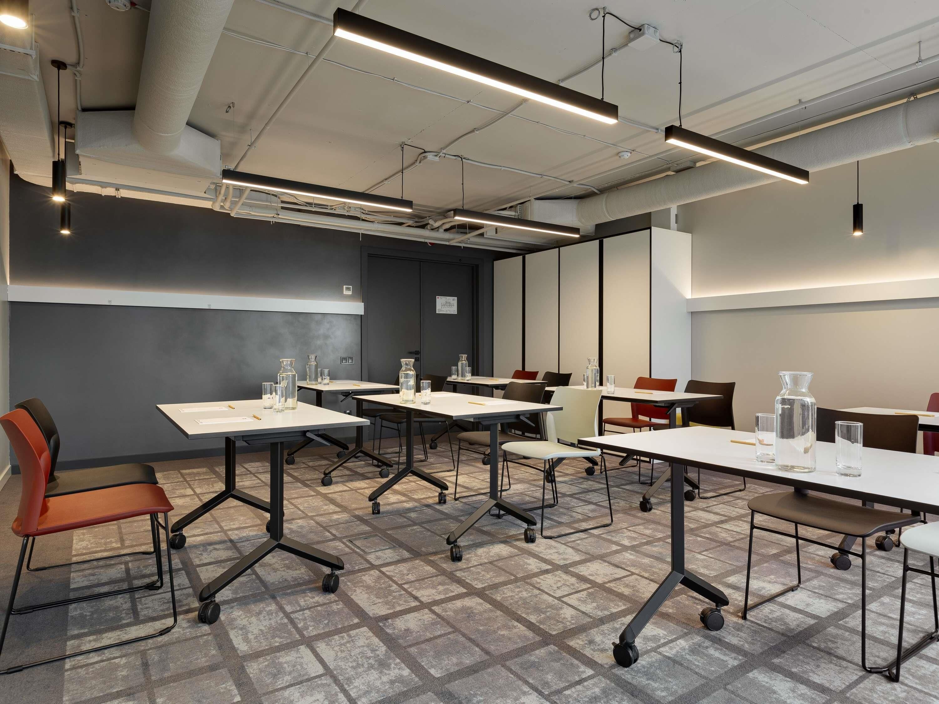 Une salle de conférence équipée de tables, de chaises et d’un système d’éclairage au plafond.