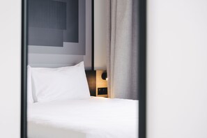 A neatly made bed with white linens and a headboard with a geometric design.