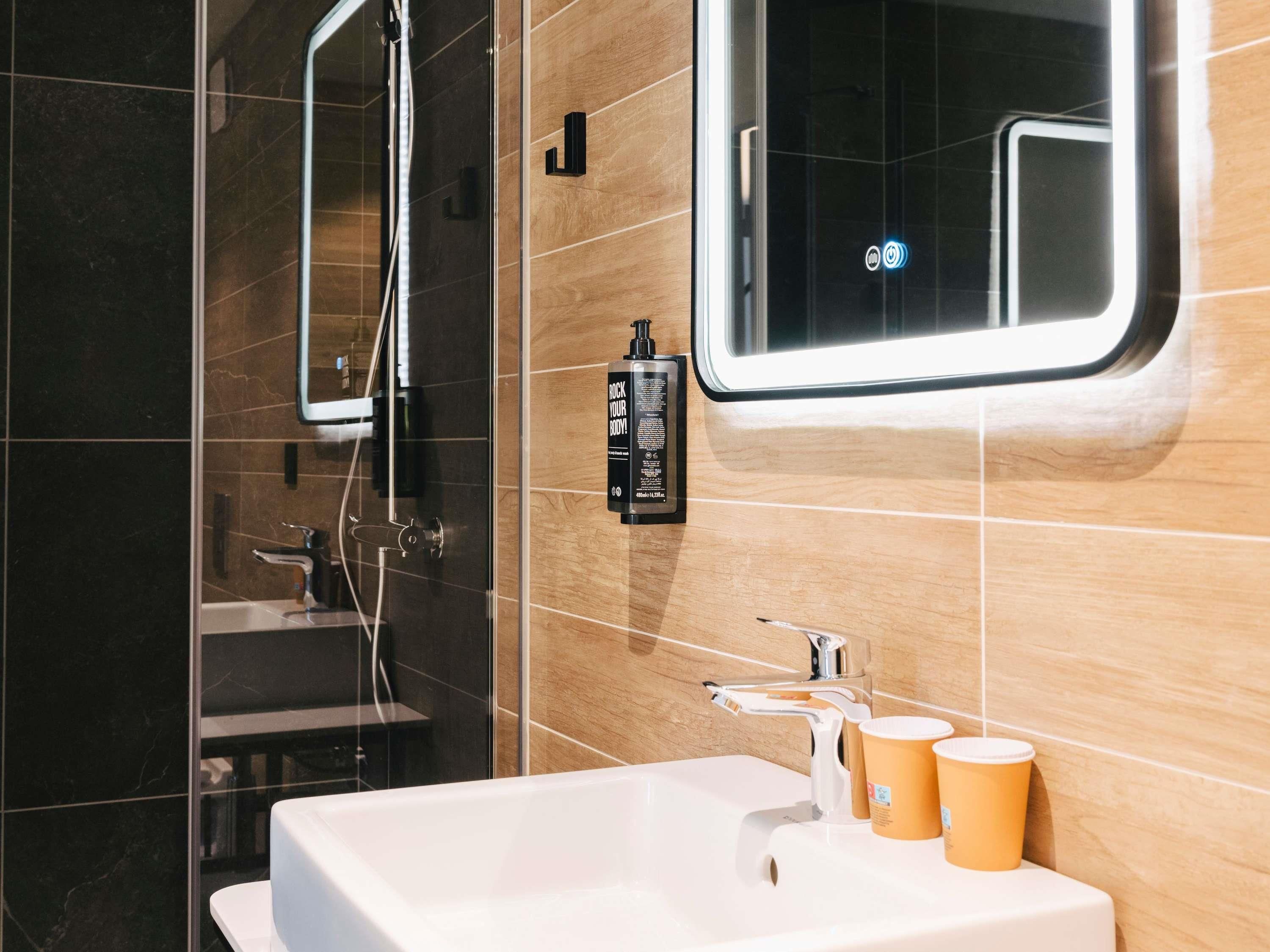 A modern bathroom with a glass shower enclosure, a white sink, and a mirror.