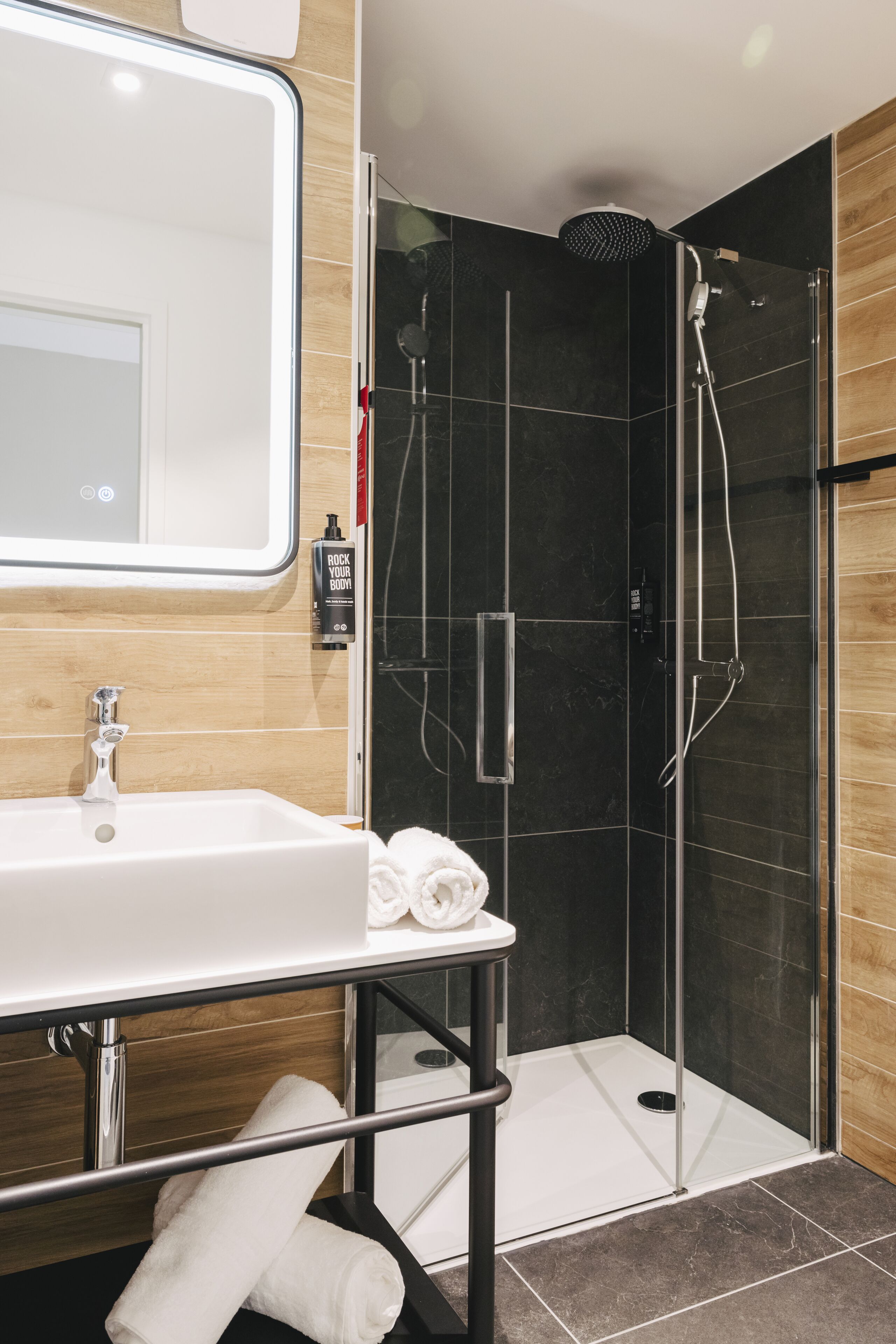 A modern bathroom with a glass-enclosed shower, a white sink, and a mirror above it.