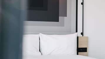 Een bed met witte beddengoed, een hoofdbord met een zwart metalen frame en een wandlamp.