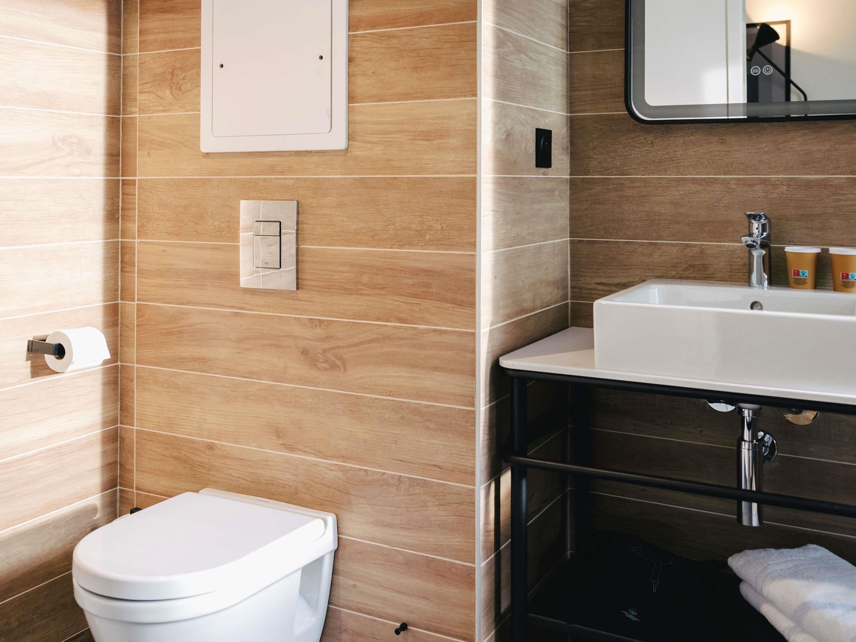 A bathroom with a toilet, sink, and mirror.