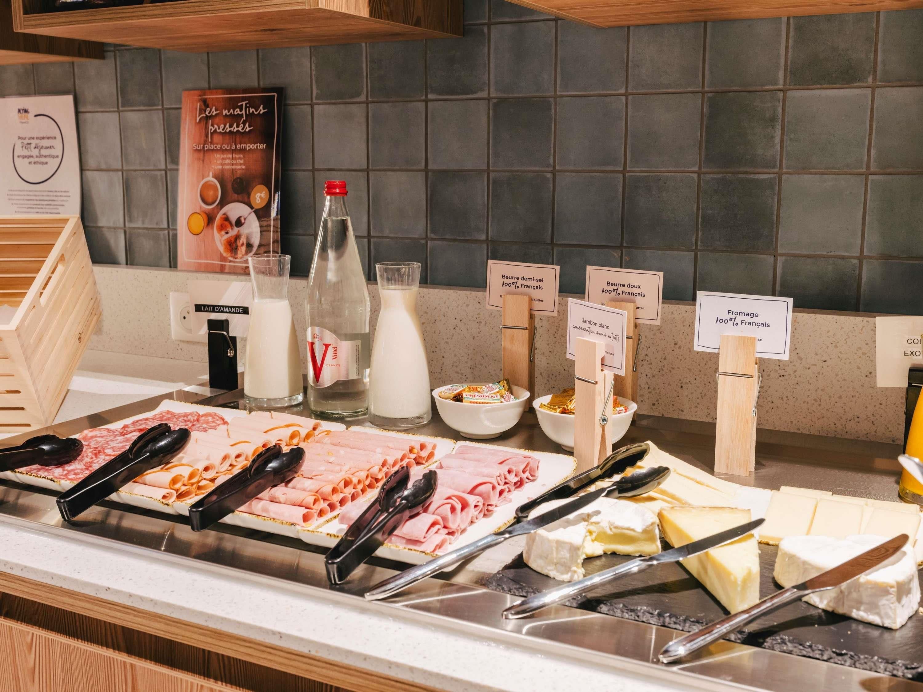 Un bufé con diversas opciones de comida, incluyendo carnes, quesos y productos lácteos, con etiquetas que especifican el tipo y origen de cada uno.