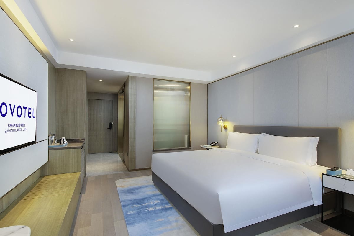 Een hotelkamer met een bed, nachtkastje, een tv waarop 'OVOTEL' staat.