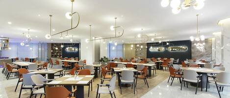 Un comedor moderno con varias mesas y sillas, luminarias colgantes y suelo de mármol.