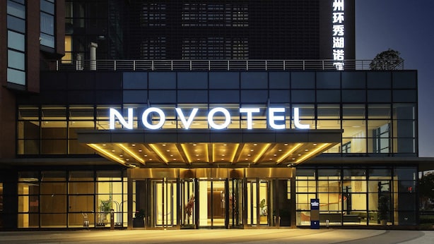Una entrada de hotel moderna con un llamativo letrero de 'NOVOTEL', puertas de cristal y una fachada bien iluminada.