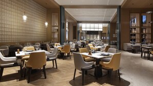 A spacious restaurant with high ceilings, modern lighting, and a variety of seating arrangements. - Novotel Yancheng Exhibition Center (Yancheng)