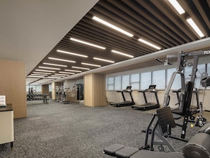 Une salle de sport équipée de tapis de course, d’appareils de musculation et d’haltères.
