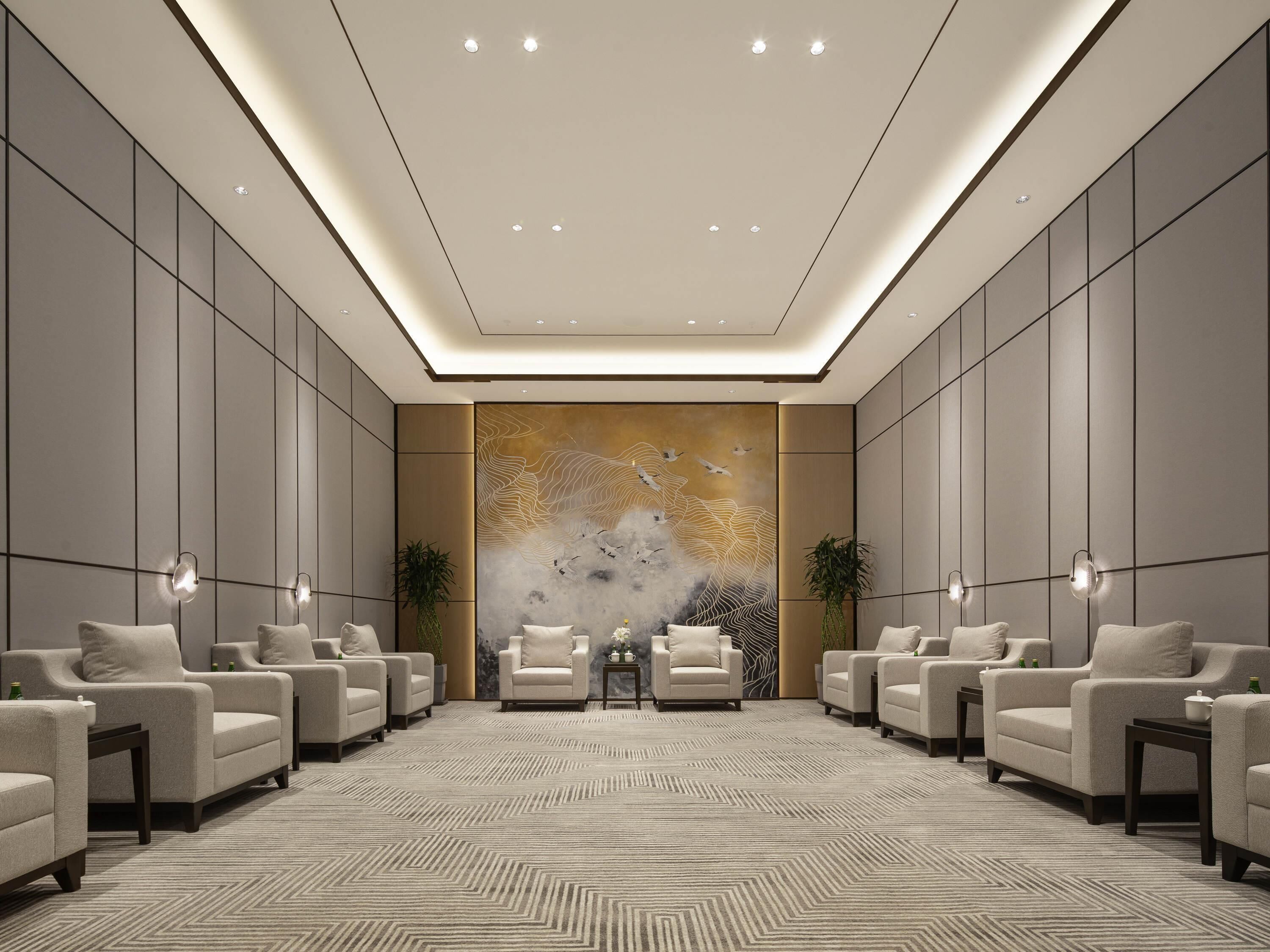 Un hall de hotel espacioso y moderno, con un amplio espacio de descanso, un mural decorativo y una alfombra estampada.