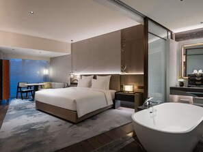 A modern hotel room with a large bed, a sitting area with a table and chairs, a separate bathroom with a freestanding bathtub, and a large mirror above the vanity. - Pullman Quanzhou Shuitou (Quanzhou)