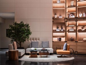 A modern living room with a sofa, coffee table, and a bookshelf filled with books and decorative items. - Pullman Quanzhou Shuitou (Quanzhou)