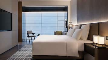 A modern hotel room with a large bed, a TV, a desk, and a chair.