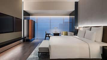 A modern hotel room with a large bed, bedside tables, a desk, and a view of the cityscape.