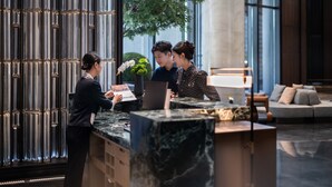 A reception desk with a marble top, a vertical light fixture, and a potted plant. - Pullman Quanzhou Shuitou (Quanzhou)