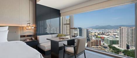 Una habitación de hotel moderna con una cama, un escritorio y vistas a la ciudad.