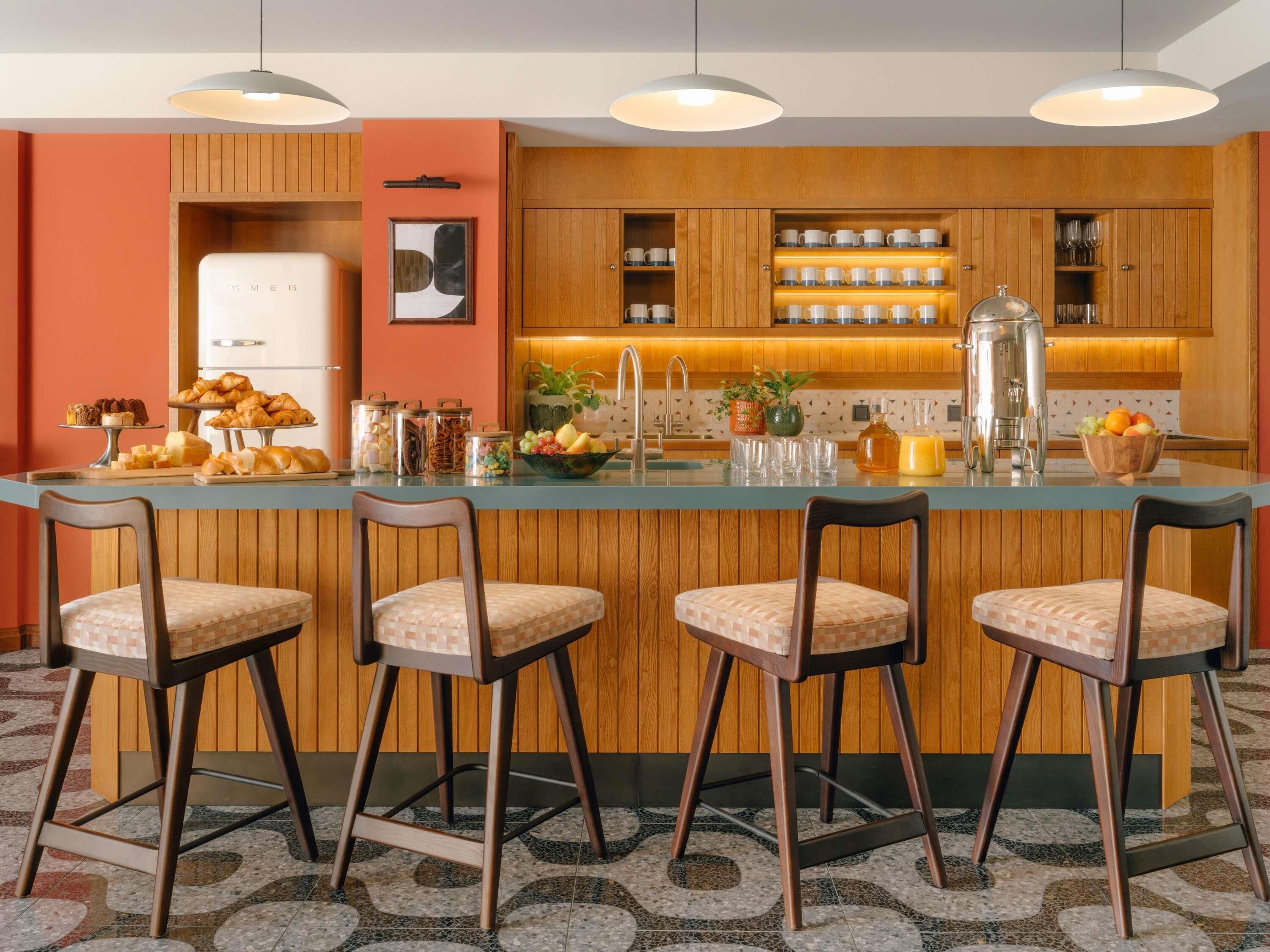 A modern kitchen with wooden cabinets, a central island with bar stools, and various kitchen appliances.