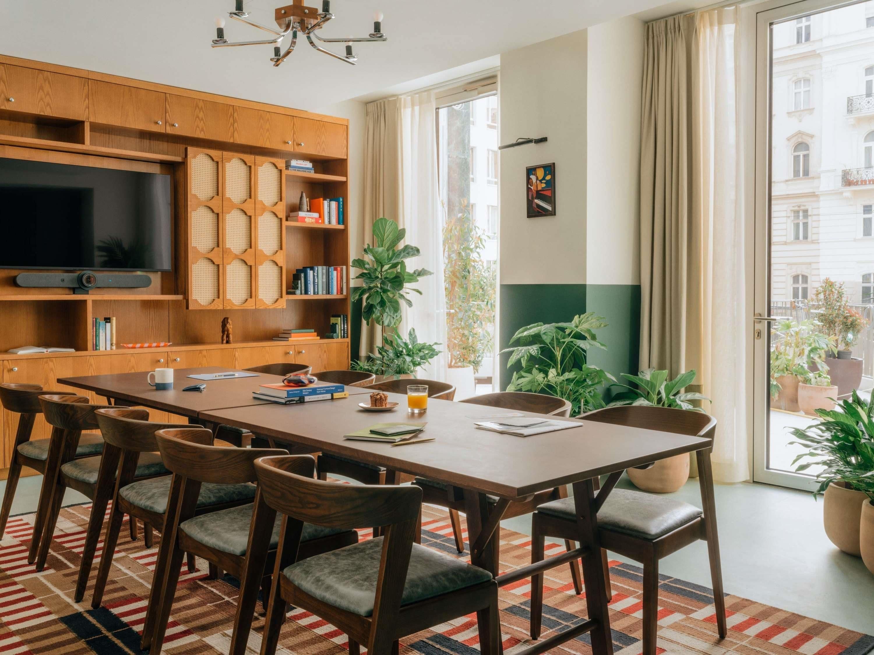 Uma sala de estar moderna com uma televisão grande, armários de madeira, estantes e uma área de jantar com cadeiras e mesa.