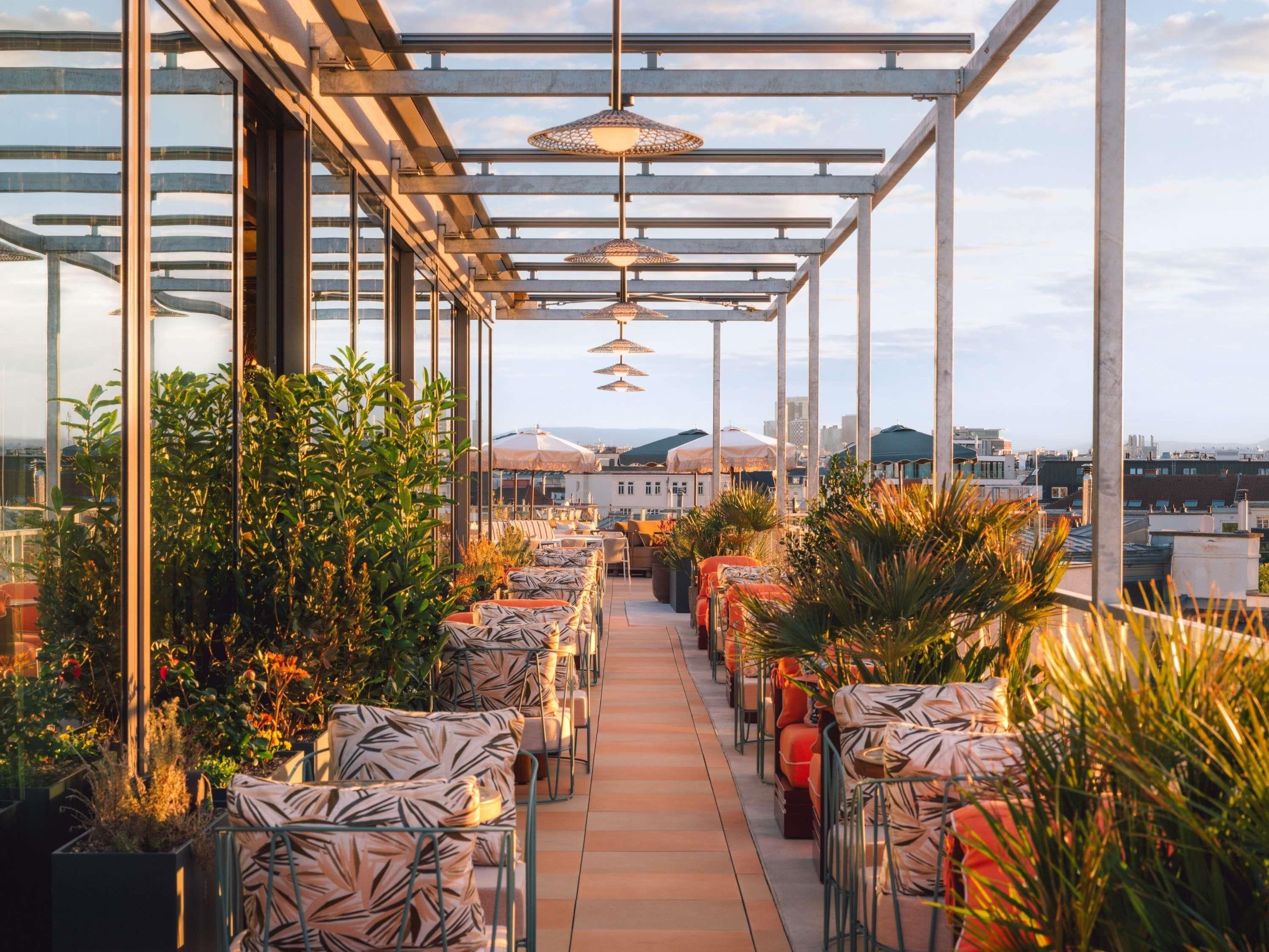 Una terraza en la azotea con mobiliario exterior, una pérgola y vistas de la ciudad.