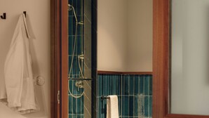 A bathroom with a shower, a towel rack, and a wooden door frame.
