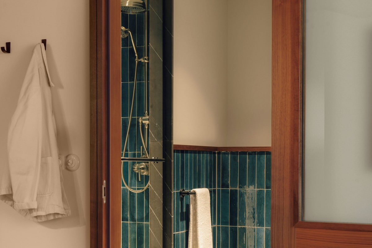Une salle de bain avec une douche, un porte-serviettes et un cadre de porte en bois.