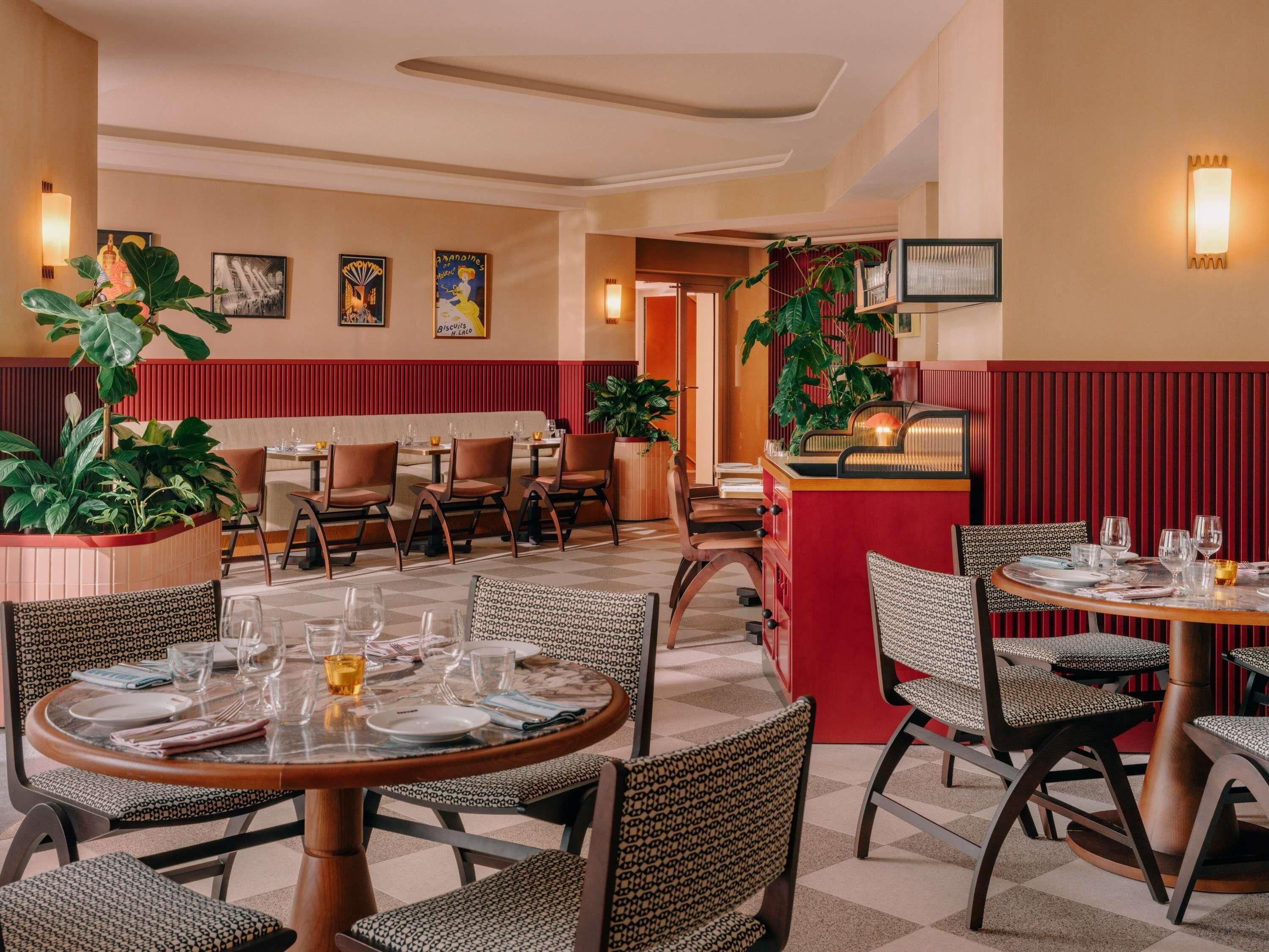 A restaurant with round tables and booths, featuring a mix of patterned and plain upholstery.