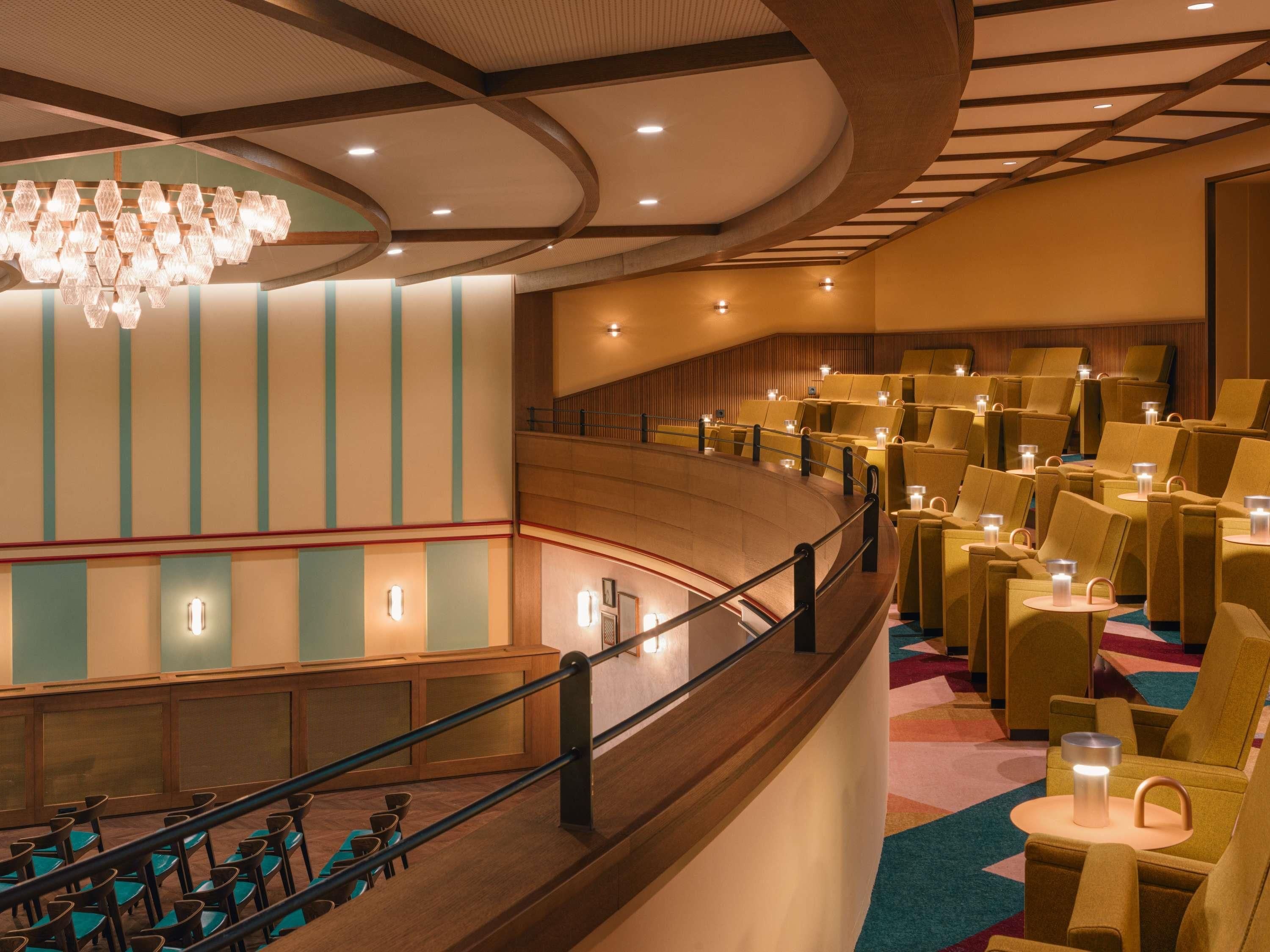A hotel lobby with a curved staircase, seating areas, and a chandelier.