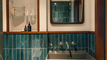 Casa de banho com lavatório, espelho e prateleiras com produtos de higiene pessoal.