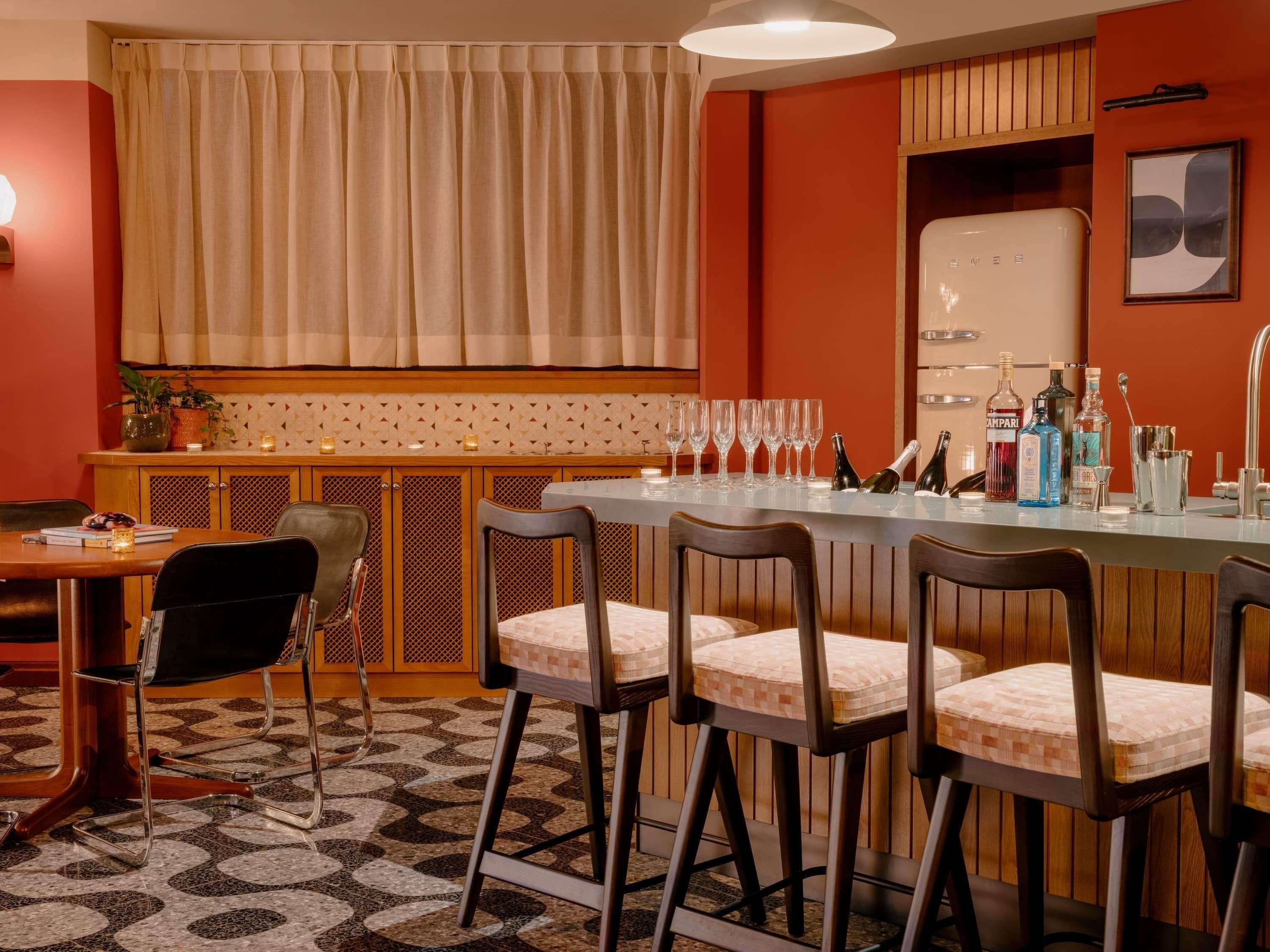 Una zona de bar con taburetes, una barra y una variedad de botellas.