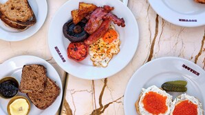 A breakfast spread with various dishes on plates, including toast, eggs, bacon, and caviar.