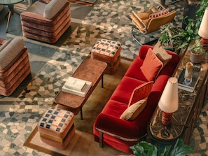 Un salon moderne avec un canapé rouge, des poufs en bois, une table basse et un sol à motifs.