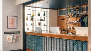 A reception area with a wooden counter, a computer, and shelves with various items.