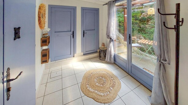 A room with a tiled floor, a woven rug, a door, and a view of greenery outside. - Amazing home in Asté with WiFi (Asté)