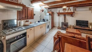 A kitchen with a stove, oven, sink, and a wood-burning stove. - Amazing home in Asté with WiFi (Asté)